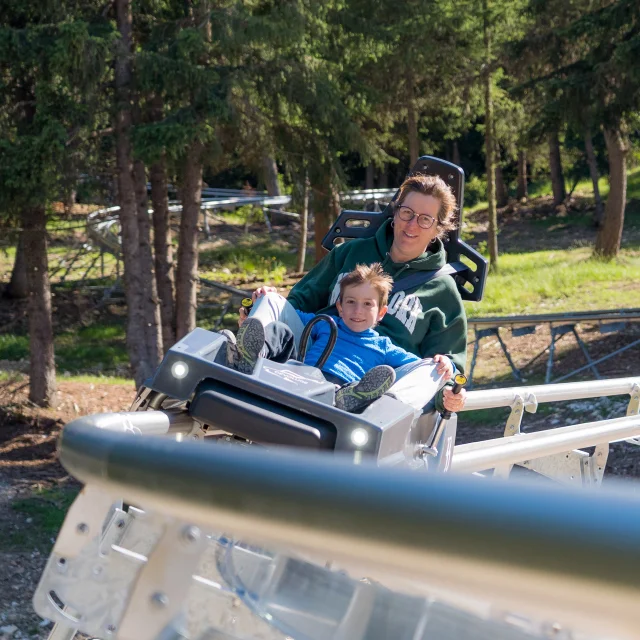 Une femme et son fils dévalent la pente sur la luge 4 saisons de Superdévoluy.