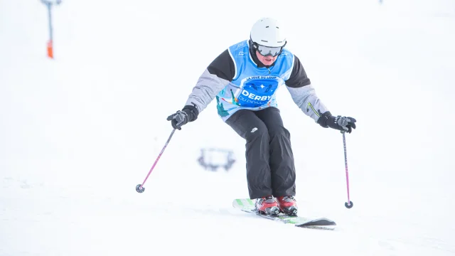 Un skieur en monoski descendant une piste.