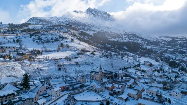 Luchtfoto van het besneeuwde dorp Saint-Étienne-en-Dévoluy met zijn kerk, huizen en de hellingen van het Dévoluy-massief op de achtergrond in de Hautes-Alpes.