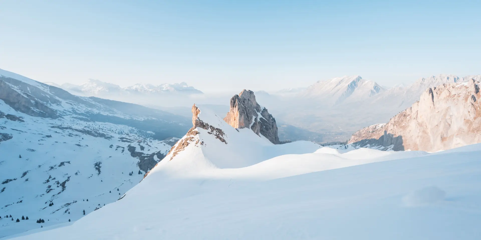 Snow-covered ridge of the Vallon d’Âne in the Dévoluy massif, with rocky peaks emerging from the snow under a clear blue sky.
