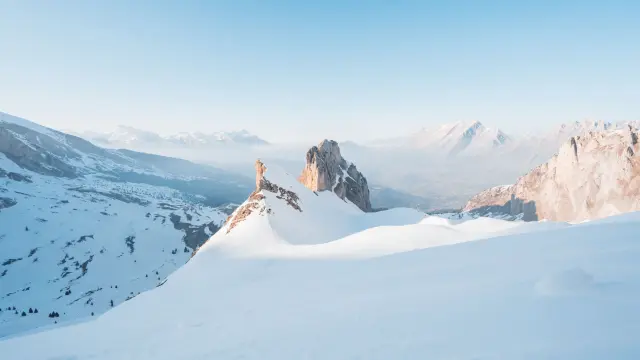 Snow-covered ridge of the Vallon d’Âne in the Dévoluy massif, with rocky peaks emerging from the snow under a clear blue sky.