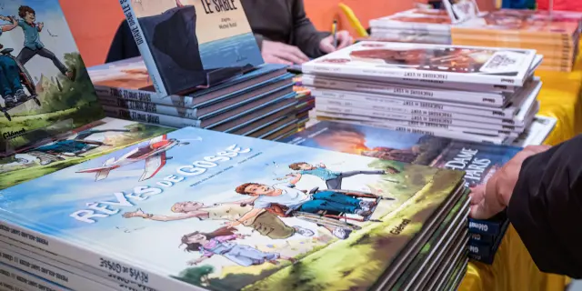 Stapels stripalbums uitgestald op een tafel tijdens Les Givrés de la BD in Le Dévoluy.