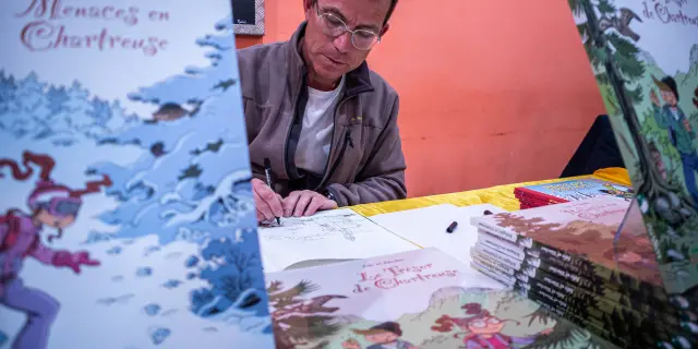 Een striptekenaar maakt een tekening en signeert een album tijdens Les Givrés de la BD in Le Dévoluy.