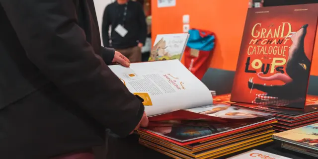 Een bezoeker bladert door stripalbums op een stand tijdens Les Givrés de la BD in Le Dévoluy.