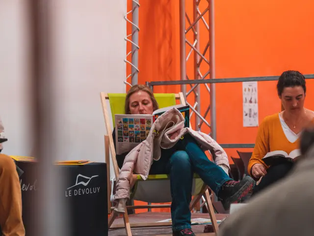 Des visiteurs lisent des bandes dessinées assis dans un espace détente lors de l’événement Les Givrés de la BD au Dévoluy.
