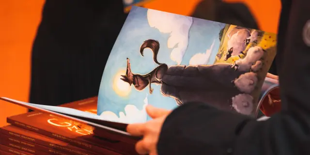 Een bezoeker bladert door een geïllustreerd stripboek tijdens Les Givrés de la BD in Le Dévoluy.