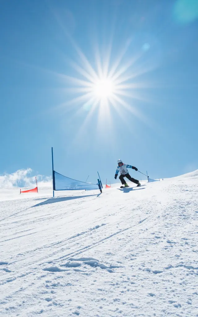 Kinderen en volwassenen nemen deel aan een familieslalom op een zonnige skipiste in Le Dévoluy.