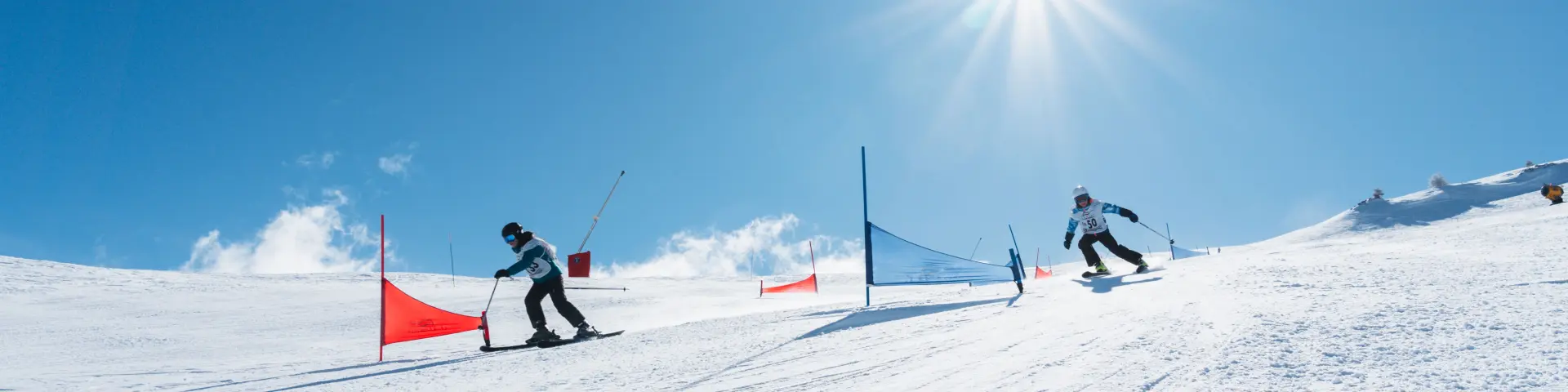 Enfants et adultes participant à un slalom de ski familial sur une piste ensoleillée du Dévoluy.