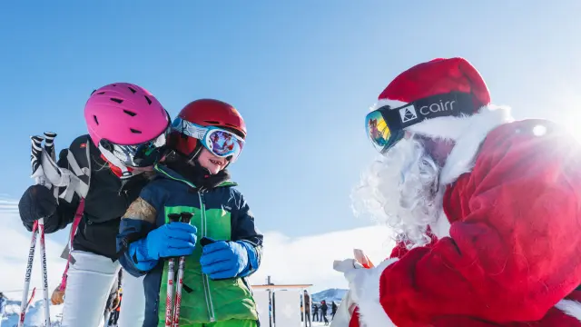 Een kind op ski’s ontmoet de Kerstman op de besneeuwde pistes van Le Dévoluy.