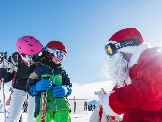 Un enfant à ski rencontre le Père Noël sur les pistes enneigées du Dévoluy, en famille.