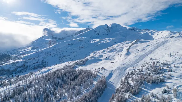 Vue aérienne du domaine skiable du Dévoluy enneigé, entre forêts et pistes de ski.