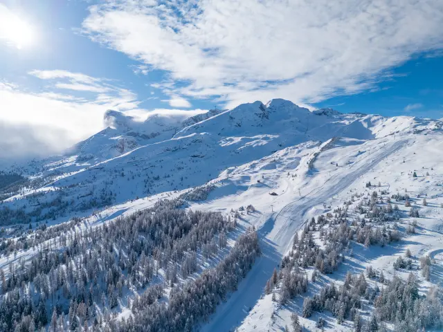 Luchtzicht op het besneeuwde skigebied van Le Dévoluy, tussen bossen en skipistes.