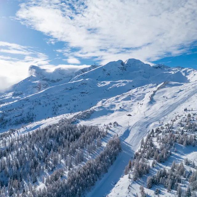 Luchtzicht op het besneeuwde skigebied van Le Dévoluy, tussen bossen en skipistes.