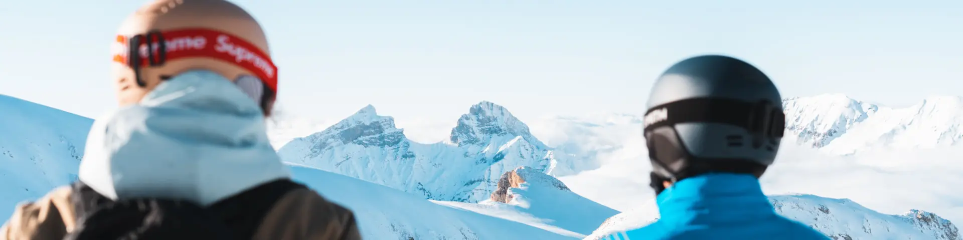 Two skiers looking at a snowy mountain landscape from the slopes of Le Dévoluy.