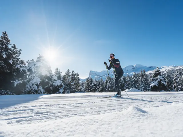 Een langlaufer glijdt over een geprepareerde piste in een besneeuwd bos in Le Dévoluy.