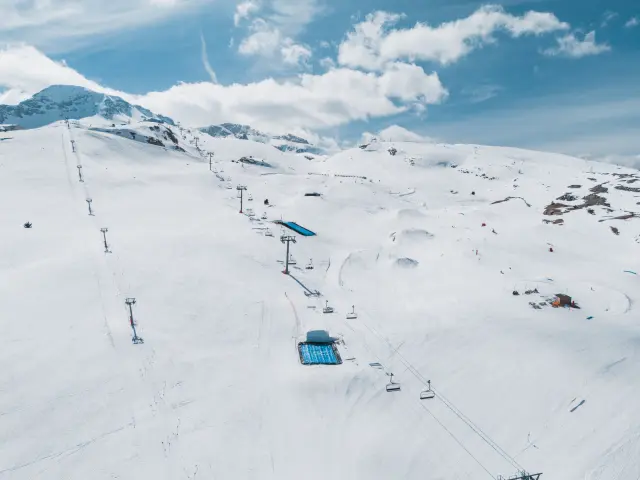 Vue aérienne du snowpark Fly Zone avec modules, big air et pistes enneigées sur le domaine skiable du Dévoluy.