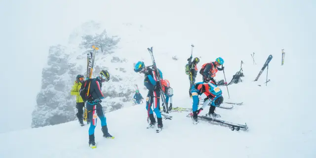 Ski-alpinisten maken hun uitrusting klaar in mistige omstandigheden op een besneeuwde bergkam.