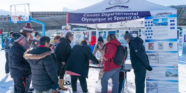 Des visiteurs découvrent une exposition retraçant les Jeux Olympiques d’hiver, installée en plein air sur la neige.
