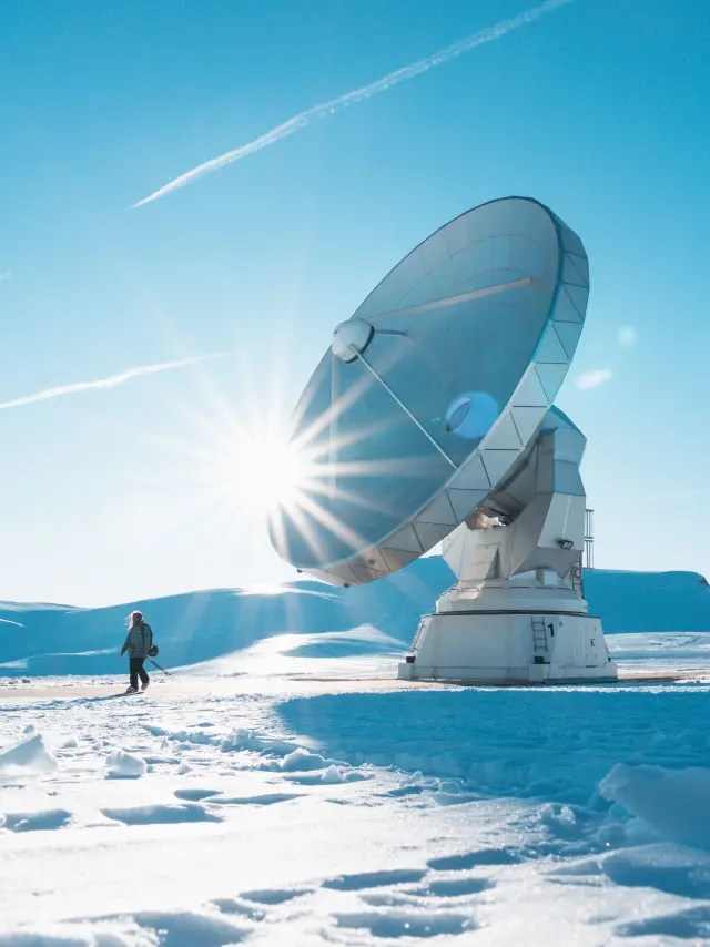 Grandes antennes paraboliques scientifiques sur un plateau enneigé avec soleil rasant et ciel bleu.