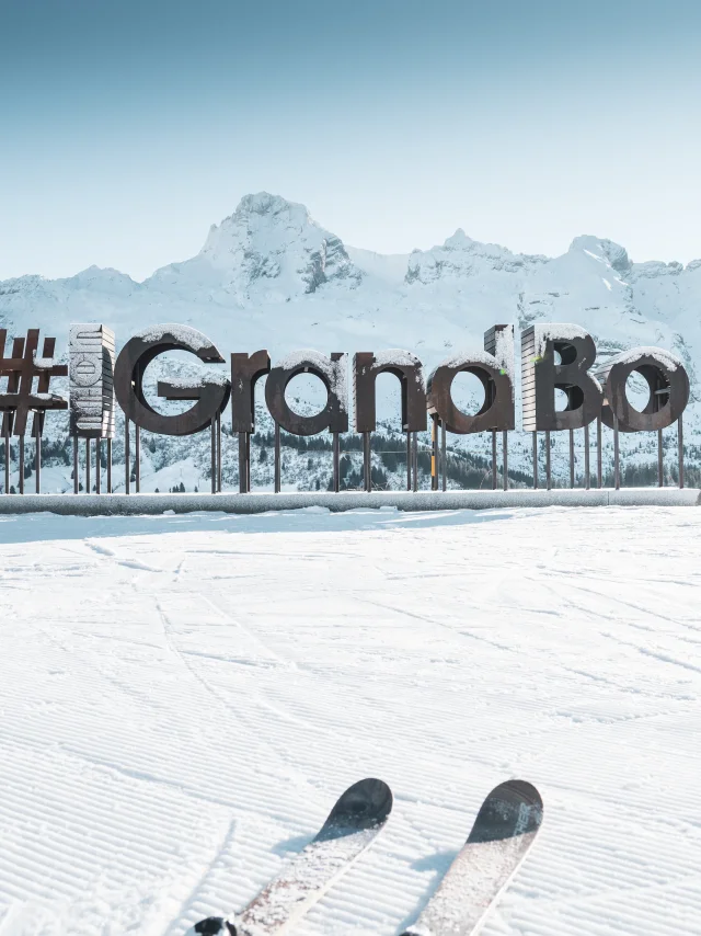 des lettres en bois avec du givre forment le mot mongrandbo devant la chaine des aravis enneigée