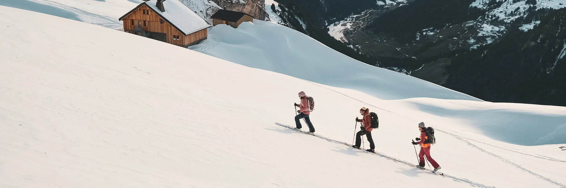 Hikers advancing in the snow, Gramusset refuge and Bouchet valley in the background.