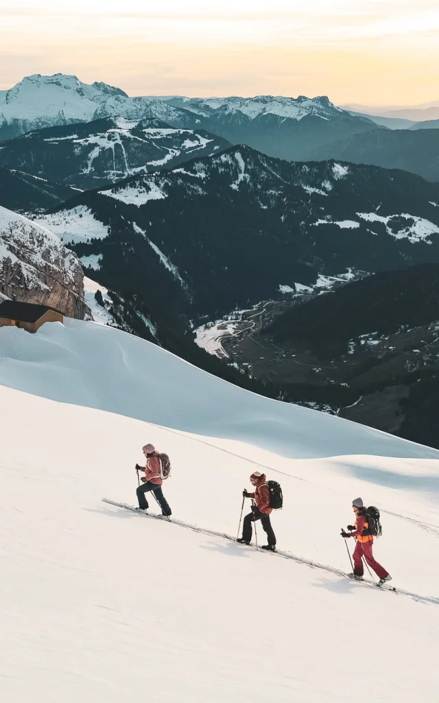 Hikers advancing in the snow, Gramusset refuge and Bouchet valley in the background.