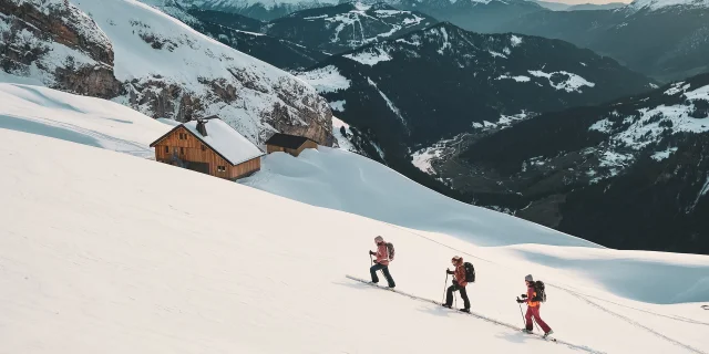 Randonneurs skieurs avançant dans la neige, refuge Gramusset et vallée du Bouchet en arrière-plan.