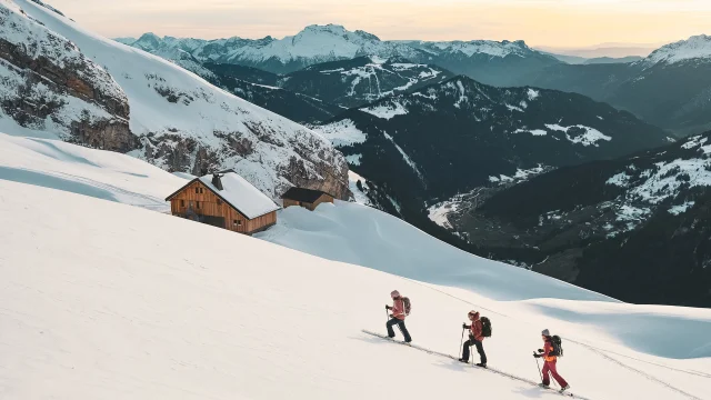 Hikers advancing in the snow, Gramusset refuge and Bouchet valley in the background.