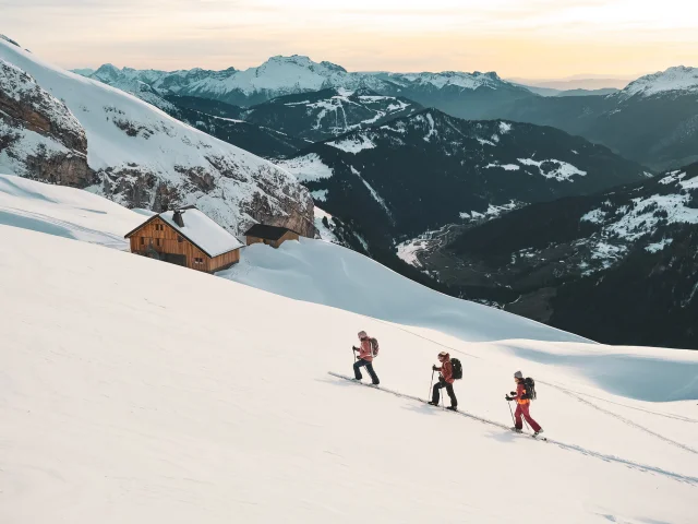 Hikers advancing in the snow, Gramusset refuge and Bouchet valley in the background.
