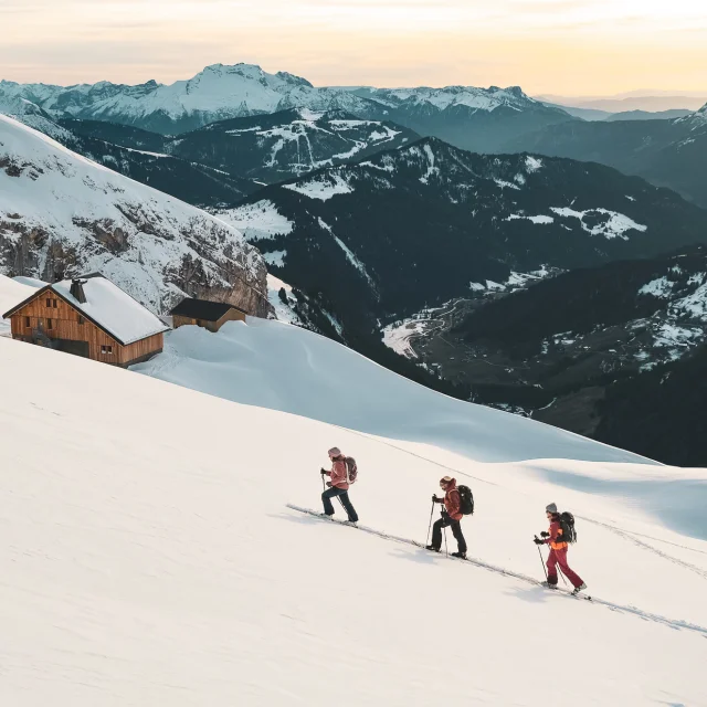 Hikers advancing in the snow, Gramusset refuge and Bouchet valley in the background.