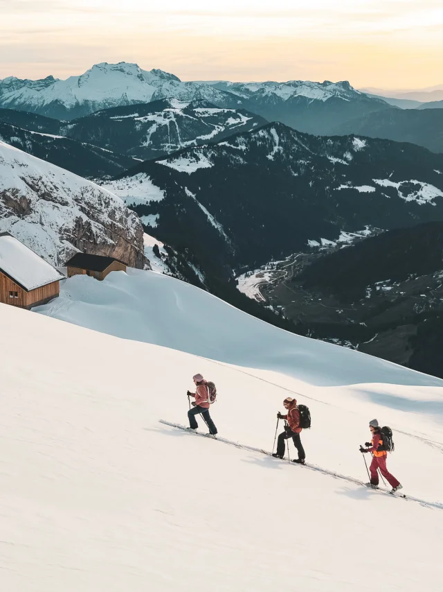 Randonneurs skieurs avançant dans la neige, refuge Gramusset et vallée du Bouchet en arrière-plan.