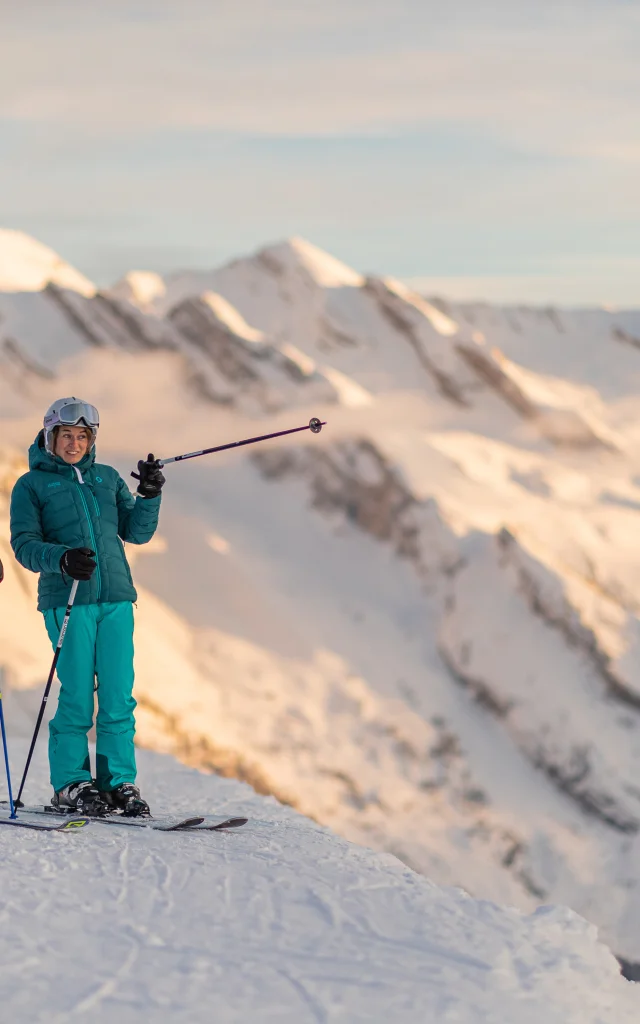 Zwei Alpinskifahrer hielten einige Minuten oben auf der Piste an, um den Sonnenuntergang und die atemberaubende Aussicht auf die Aravis-Kette zu genießen. Der eine trägt einen blau-grauen Skianzug und der andere einen türkisblauen Skianzug. Eine schöne Komplizenschaft ist zu spüren, beide lächeln. Einer der Skifahrer zeigt seinem Freund mit erhobenem Stock einen Berg. Die Atmosphäre ist entspannt und die Lichter sind sehr beruhigend.