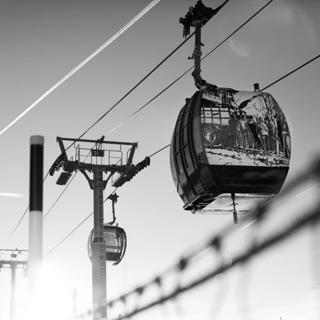 Cabine de télécabine du Grand-Bornand avec illustration artistique en noir et blanc, suspendue au-dessus de la montagne.