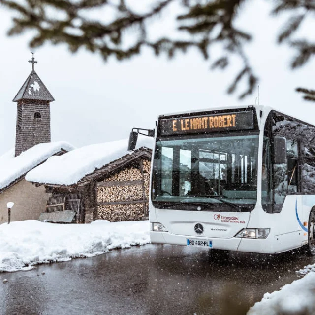 Winter shuttle service to Grand-Bornand in front of the chapel in the snow.