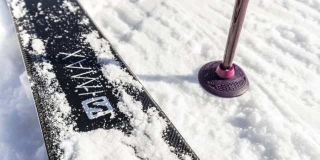 Gros plan sur un ski et un bâton planté dans la neige fraîche au Grand-Bornand, symbole de sports d’hiver et glisse en montagne.