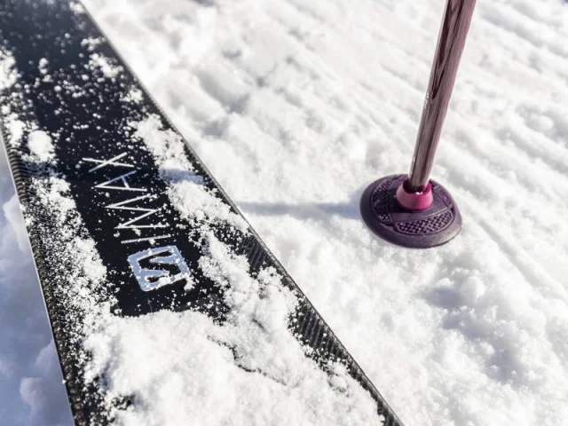 Gros plan sur un ski et un bâton planté dans la neige fraîche au Grand-Bornand, symbole de sports d’hiver et glisse en montagne.