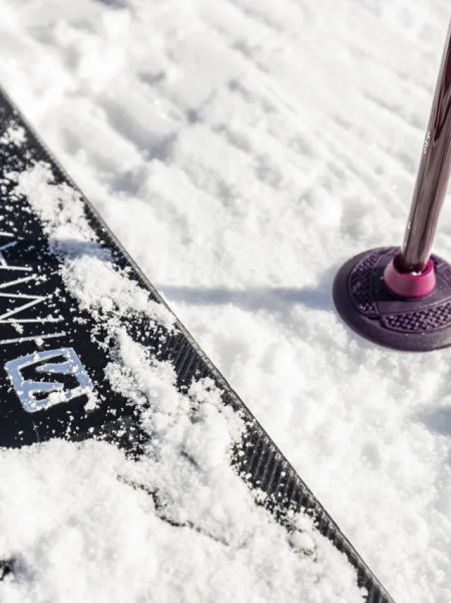 Gros plan sur un ski et un bâton planté dans la neige fraîche au Grand-Bornand, symbole de sports d’hiver et glisse en montagne.