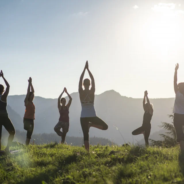 Groupe de personnes pratiquant le yoga en plein air au sommet du Lachat, face aux montagnes, au lever du soleil – Le Grand-Bornand