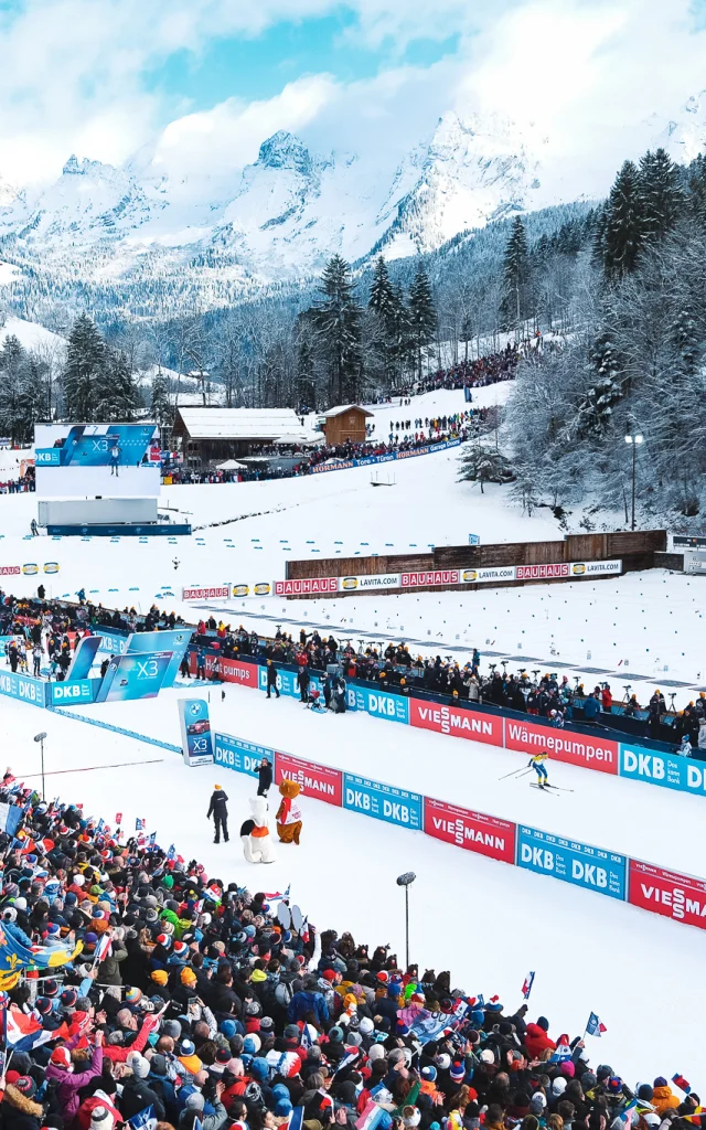 Luftaufnahme des Sylvie-Becaert-Stadions in einer verschneiten Kulisse während des Biathlon-Weltcups Annecy-Le Grand-Bornand 2024. Wir können die Begeisterung der Zuschauer auf den Tribünen sehen.