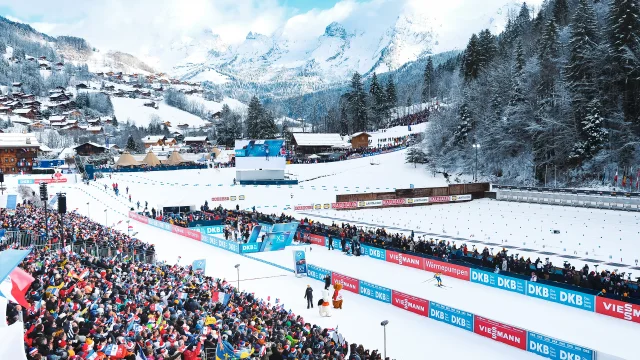 Vue aérienne du stade Sylvie Becaert dans un décor enneigé lors de la Coupe du monde de Biathlon Annecy-Le Grand-Bornand 2024. Nous pouvons voir la ferveur du public dans les gradins.
