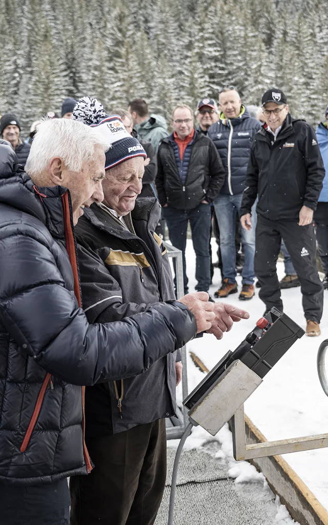 Fermeture du télésiège de la Duche en hiver 2024 avec Marcel Pernet-Solliet et Gilbert Fournier-Bidoz. Les deux hommes sont sur le point d'appuyer sur le bouton d'arrêt avec un groupe de personnes en arrière plan.