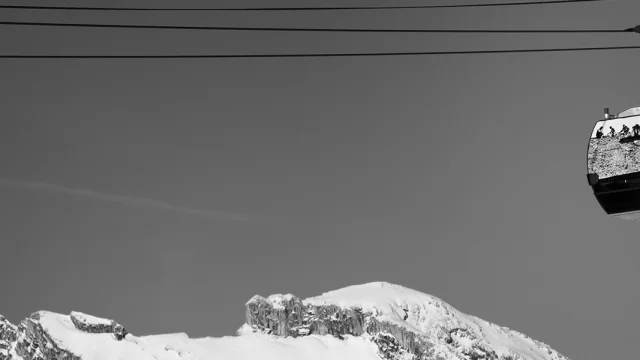 Two suspended Grandborama cabins, decorated with works of art, with the snow-capped peaks of Grand-Bornand in the background.