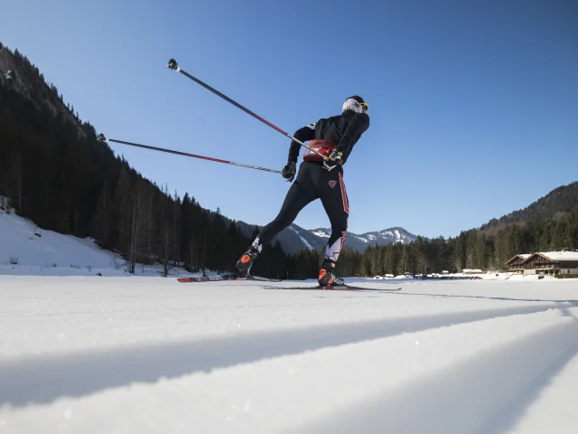 Un skieur nordique de dos fait du skating à l'auberge nordique