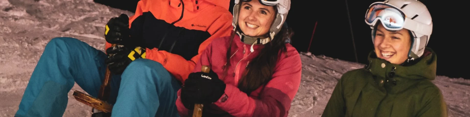 3 personnes habillés chaudement sont assises chacun sur un paret avec le sourire, la photo est prise de nuit