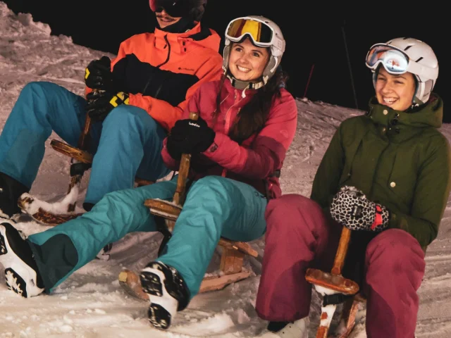 3 personnes habillés chaudement sont assises chacun sur un paret avec le sourire, la photo est prise de nuit