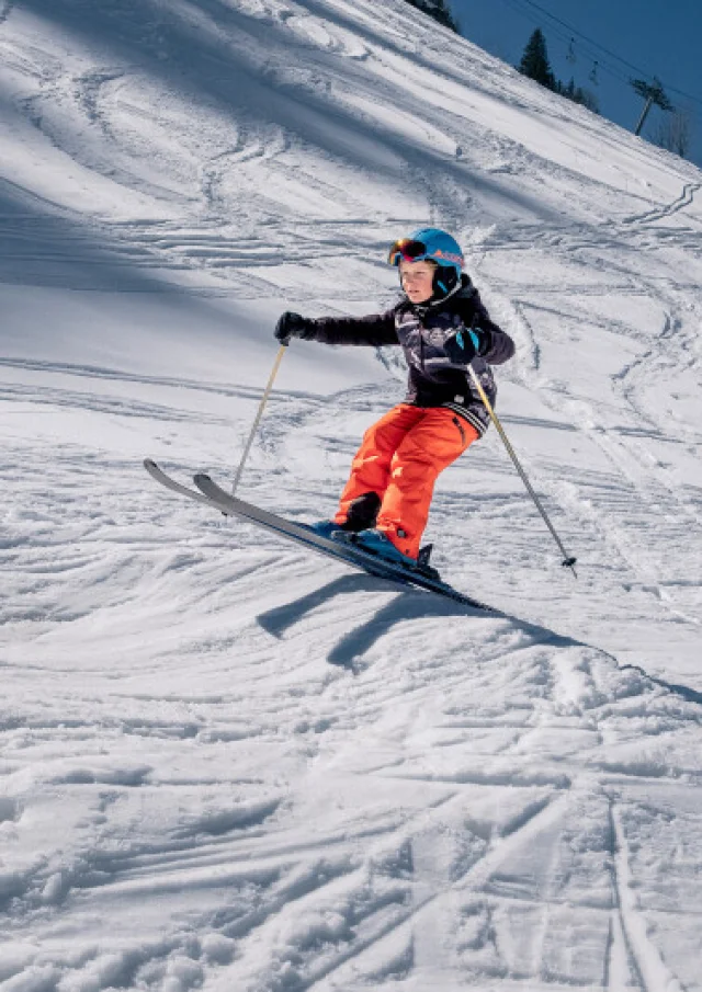 Jeune skieur descendant une piste enneigée au Grand-Bornand sur le Môm’Park