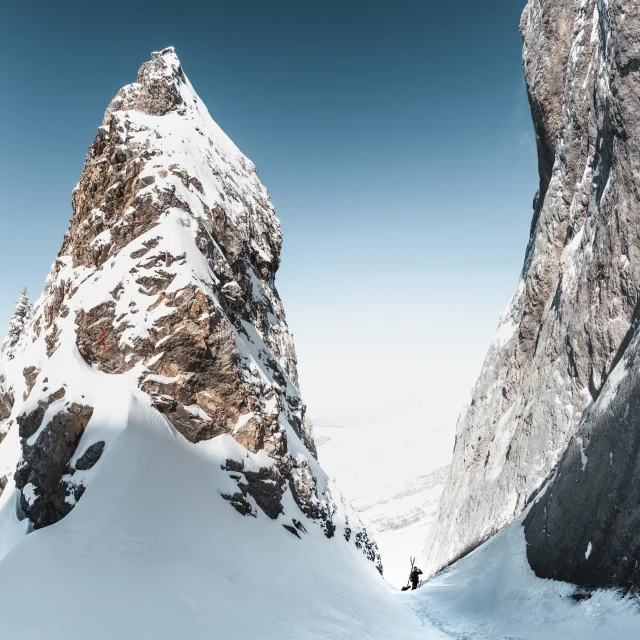 A touring skier emerges from a snow-covered mountain corridor in an atmosphere of grandeur and adventure