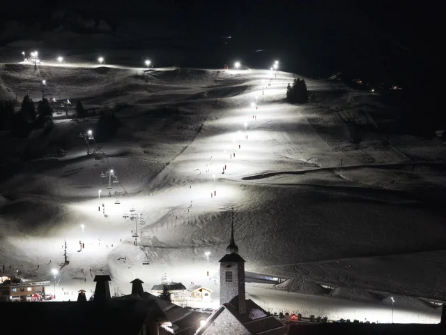 Night view of the Grand-Bornand ski area illuminated, with the emblematic church in the foreground.