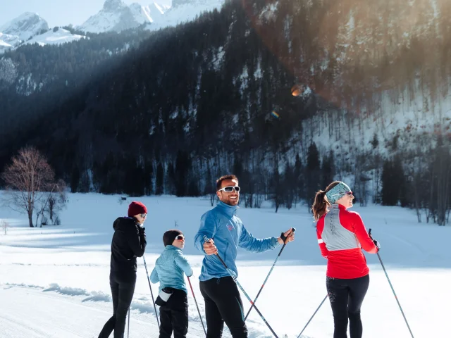 Une famille en ski de fond sur les pistes de ski nordique contemple la pointe percée au fond de la vallée du bouchet