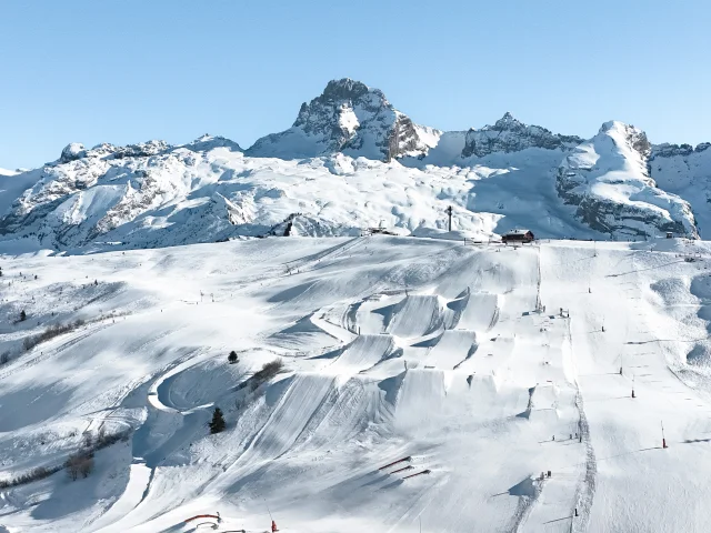 Une vue aérienne du snowpark du grand bornand et ses 6 hectares d'infrastructures freestyle avec la pointe percéeen arrière plan